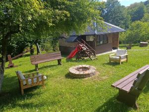 a yard with benches and a fire pit and a cabin at Hil in Rakovica