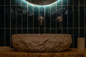 a bathroom with a stone sink and black tiled walls at Orsola Apartments in Favignana