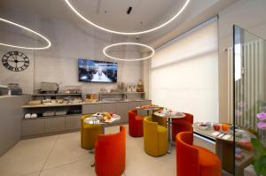 a restaurant with orange and yellow chairs and a kitchen at Hotel Nuovo Metrò in Milan