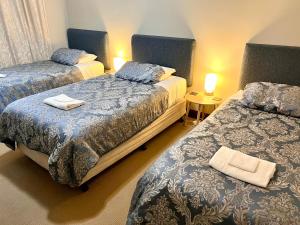 a bedroom with two beds and two tables with lamps at Bõucher Manor - Northam in Northam