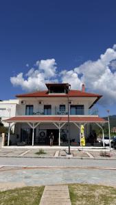 a large white building with a red roof at Sabbia Suites in Nea Vrasna