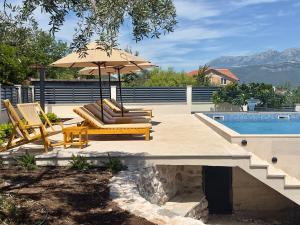 a patio with two chairs and an umbrella next to a pool at Villa Paula in Radovici