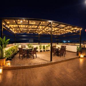 eine Terrasse mit Tischen, Stühlen und Lichtern in der Unterkunft Hill View Comforts in Mysore