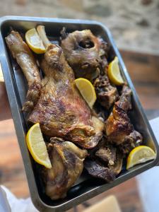 a pan of food with chicken and lemon slices at Sylbica Guesthouse in Tropojë +19 photos