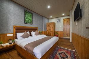 a bedroom with a large bed and a flat screen tv at The Suffer Heights l Open Air Lawn l Rooms and Cafe l Kufri by Exotic Stays in Kūfrī