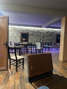 a room with tables and chairs and a stone wall at Sylbica Guesthouse in Tropojë