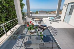 a patio with a glass table and chairs on a balcony at Me & U - הווילה שלי בכנרת in Tel Kazir