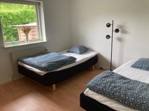 two beds in a room with a window at Lille hus i Sydbyen in Silkeborg