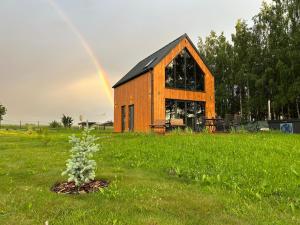 a wooden barn with a rainbow in the background at OAK House domek z balią w Serskim Lesie in Las Dalny