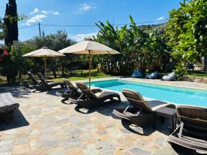a group of chairs and umbrellas next to a pool at Cottage & private swimming pool in Poros