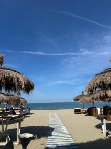 a beach with some straw umbrellas and the ocean at Avela Beach Apartments in Durrës
