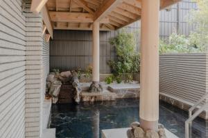 an outdoor pool with a waterfall and a wooden pergola at Oarai Park Hotel in Oarai