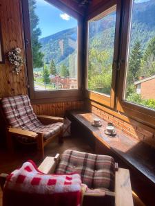 a room with two chairs and a couch and windows at Chalet Costa Rotian in Commezzadura