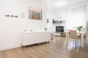 a white living room with a table and a tv at Aura Station Ciampino 'Roma, StazioneFS, Aeroporto' in Ciampino