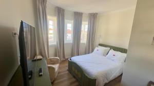 a bedroom with a bed and a chair and windows at Pink-Shell in Santiago de Riba-Ul