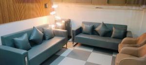 a waiting room with two blue couches and two chairs at hotel elite inn in Greater Noida