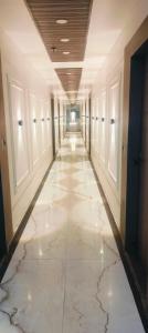 a hallway in a building with marble floors and ceilings at hotel elite inn in Greater Noida