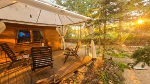 a wooden deck with two chairs and an umbrella at Pensjonacik Ogrody in Pierzchno