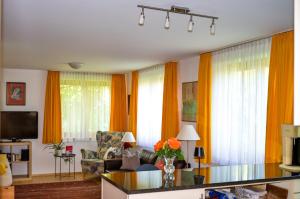a living room with orange curtains and a glass table at Apartment Denk in Bregenz