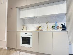 a white kitchen with white cabinets and a sink at Apartament DeLuxe Zamość Prywatny parking podziemny in Zamość