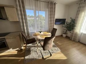 a dining room with a table and chairs and a window at Apartamentai šalia baseino in Palanga
