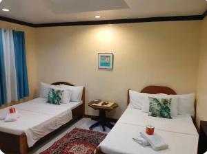 a hotel room with two beds and a table at Ennas Place guest house in Coron