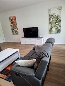 a living room with a black leather couch and a television at Ferienwohnung Bever in Bad Karlshafen