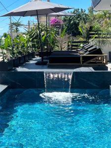 a swimming pool with an umbrella and blue water at Apartments Sadiku with swimming pool & jacuzzi in Sarandë