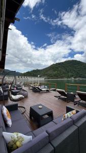 a deck with couches and tables and a view of the water at VILLAGEbythelake Bicaz in Bicaz