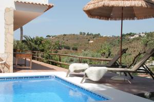 ein Swimmingpool mit Sonnenschirm, Stühlen, Tisch und Sonnenschirm in der Unterkunft Marimonta in Cómpeta