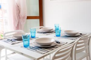 a white table with plates and blue glasses on it at Ca'vio Beach Pool in Cavallino-Treporti +28 photos