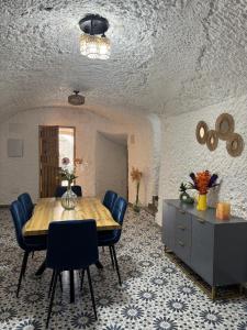 a dining room with a wooden table and blue chairs at Cueva Pilar in Graena +10 photos