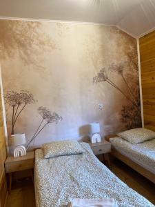 a bedroom with two beds and a wall with flowers at Rajskie Domki in Sadowie