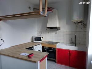 a small kitchen with red cabinets and a counter top at Appartement avec terrasse 42m2 in Saint-Martin-de-Valamas