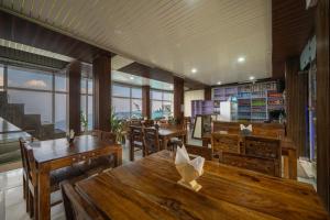 a restaurant with wooden tables and chairs and windows at The Misty Heights l Rooms and Restaurant l Family Groups & Events l Open Air Lawn l Kufri by Exotic Stays in Kūfrī