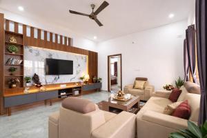 ein Wohnzimmer mit Sofas und einem Flachbildfernseher in der Unterkunft Hill View Comforts in Mysore
