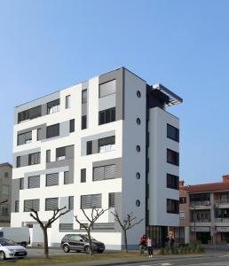 un edificio blanco con coches estacionados frente a él en Hostel Villa Domus en Koper