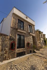 an old stone building with windows on a street at Shire Küçükköy in Ayvalık