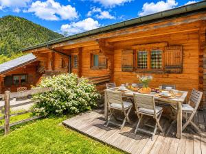 a wooden deck with a table and chairs in front of a log cabin at Clevie in Morzine