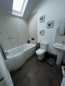 a bathroom with a tub and a toilet and a sink at Y Mor Cosy Apartment in Tywyn +16 photos
