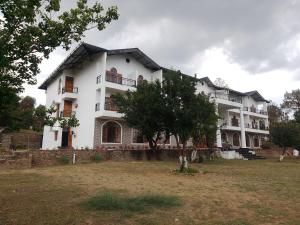 a large white house with a tree in front of it at The Kalindi's Resort, Almora in Almora