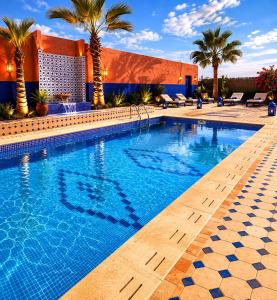a swimming pool with palm trees and a building at villa Oasis Rouge Sable in Marrakesh