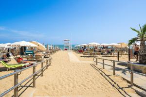 a sandy beach with chairs and umbrellas and the ocean at Hotel La Fenice in Lido di Jesolo