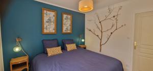 a bedroom with a purple bed and a blue wall at Le Fourneau Rond in Soings-en-Sologne