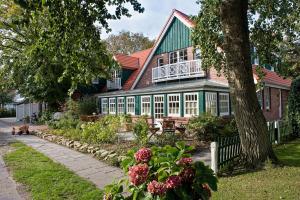 a house with a green roof and a tree at Hotel Inselfriede in Spiekeroog