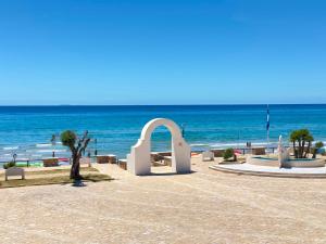 a beach with a white arch in front of the ocean at Hotel Marconi in Sperlonga