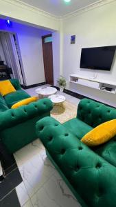 a living room with a green couch and a flat screen tv at Infinite Stays in Thika +6 photos