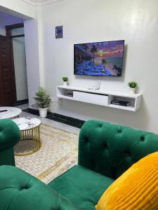 a living room with a green couch and a flat screen tv at Infinite Stays in Thika