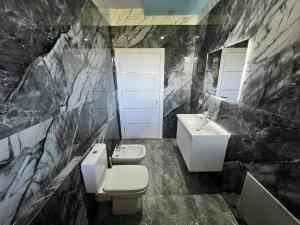 a black marble bathroom with a toilet and a sink at Host Apartments in Shkodër +56 photos