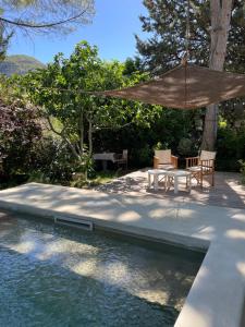 a patio with a table and an umbrella next to a pool at Maison Caramel in Condorcet